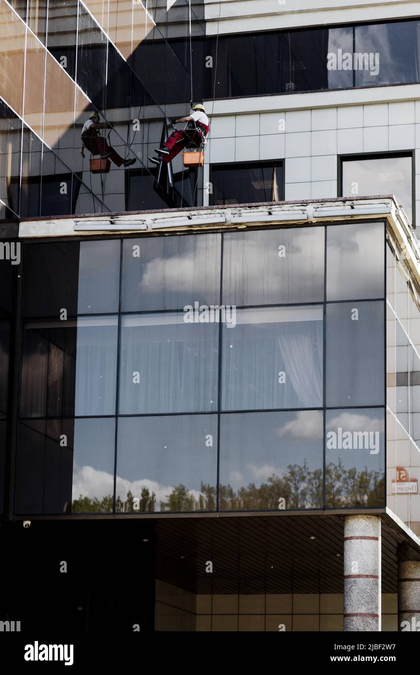 Lavare i vetri con un lavavetri . Uomo pulizia edificio ufficio Foto Stock