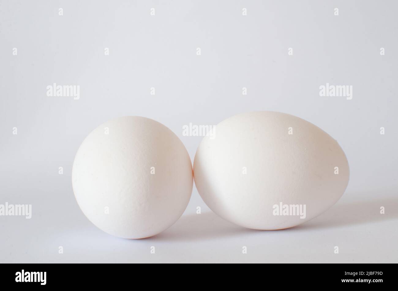 Uova, vista del profilo di due uova bianche foto in studio shot. Isolato su sfondo bianco con ombra morbida, messa a fuoco selettiva. Foto Stock