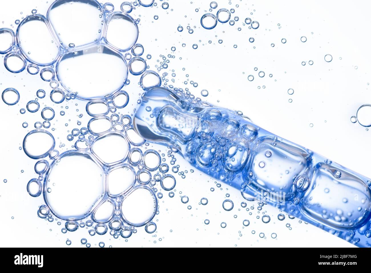 Contagocce per liquidi cosmetici macro con siero blu trasparente in pipetta con bolle isolate su sfondo bianco dall'alto Foto Stock