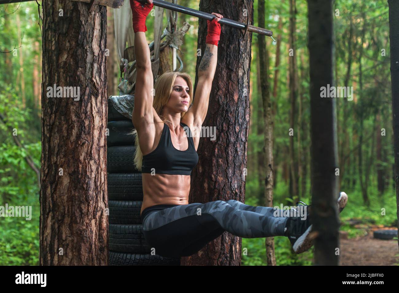 Fit donna facendo pendenti gambe sollevamenti abs muscoli esercizio su barra orisontale che si allenano all'esterno. Foto Stock