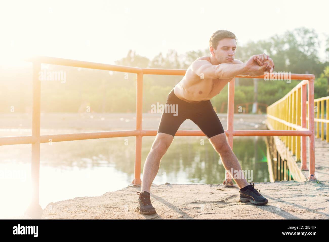 Giovane uomo sportivo che si piega in avanti e fa esercizio di stretching Foto Stock