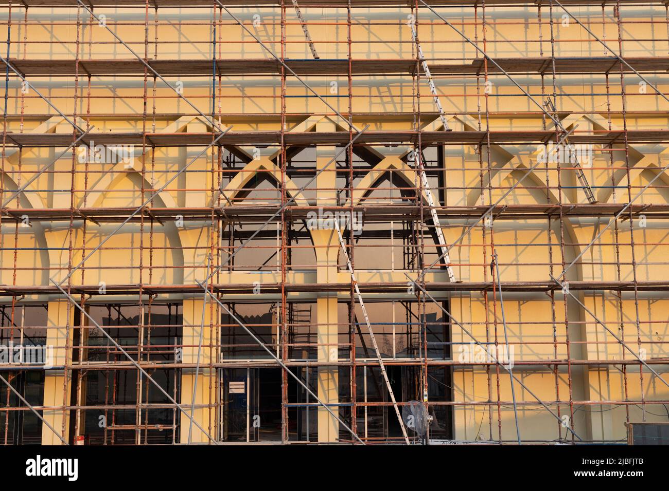 Un edificio in fase di ristrutturazione coperto da ponteggi in metallo, che mostra dettagliati lavori di costruzione e sforzi di restauro sulla facciata architettonica. Foto Stock