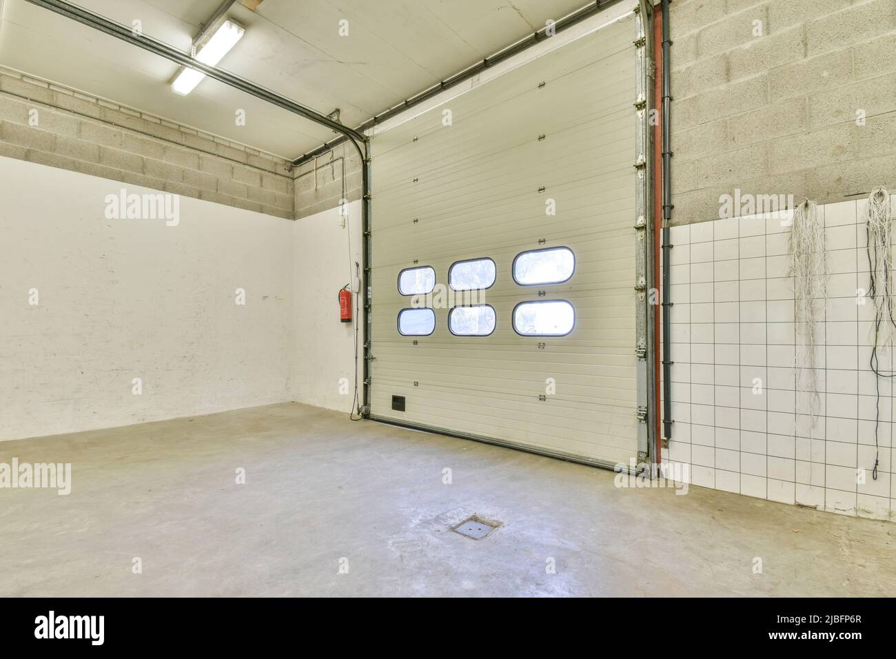 Spaziosa camera vuota con finestre di forma ovale e pareti in pietra e piastrellate in un edificio industriale Foto Stock