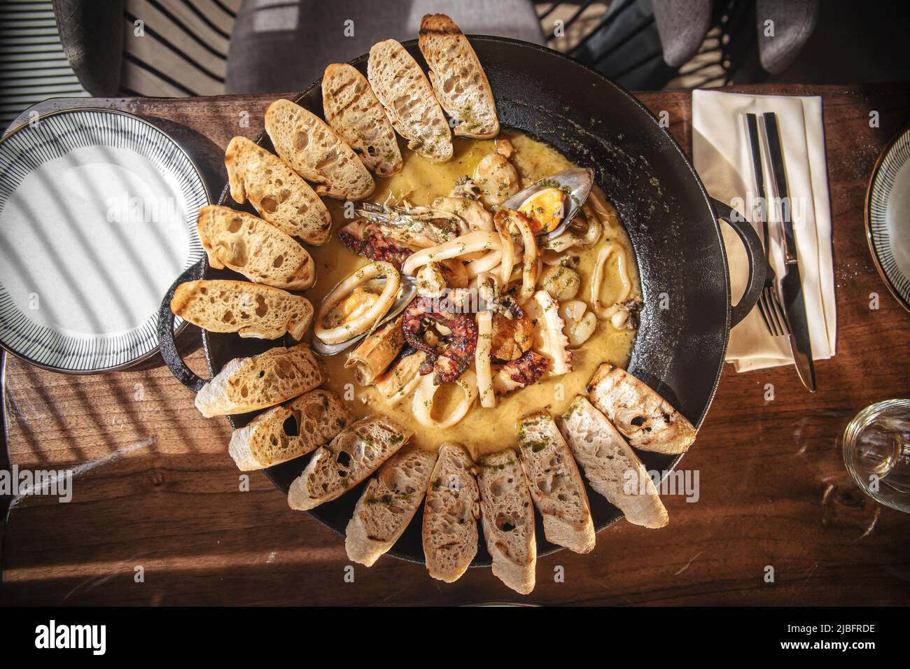 Padella di stufato di pesce con pane tostato Foto Stock