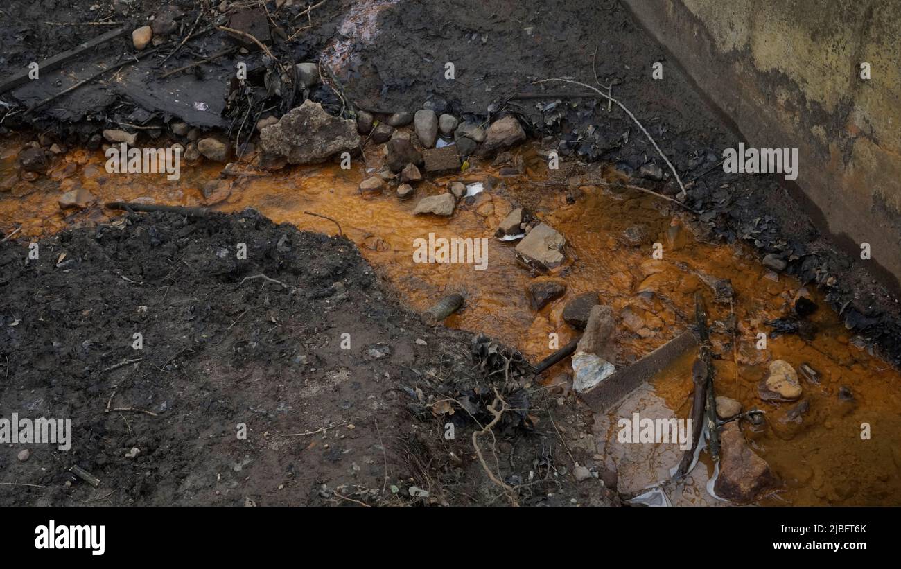 Ruscello di arancio in foresta con suolo nero. Minerale di ferro. Inquinamento. Foto Stock