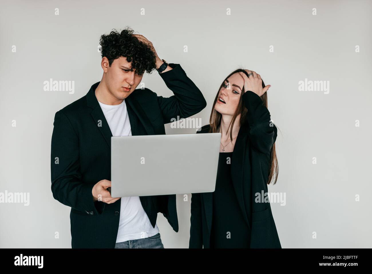 Due persone che lavorano sul portatile, problemi, depressi, sconvolto e perplesso dai risultati. In piedi su sfondo bianco Foto Stock