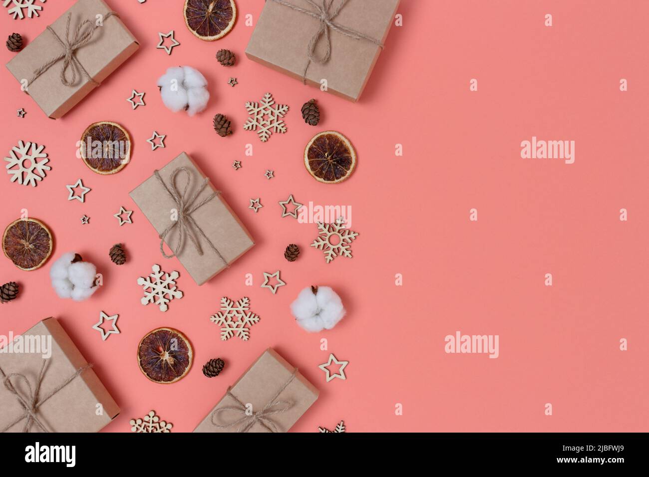 Regali avvolti e decorazioni di Natale modello su uno sfondo di corallo. Concetto di zero sprechi con spazio per il testo. Foto Stock