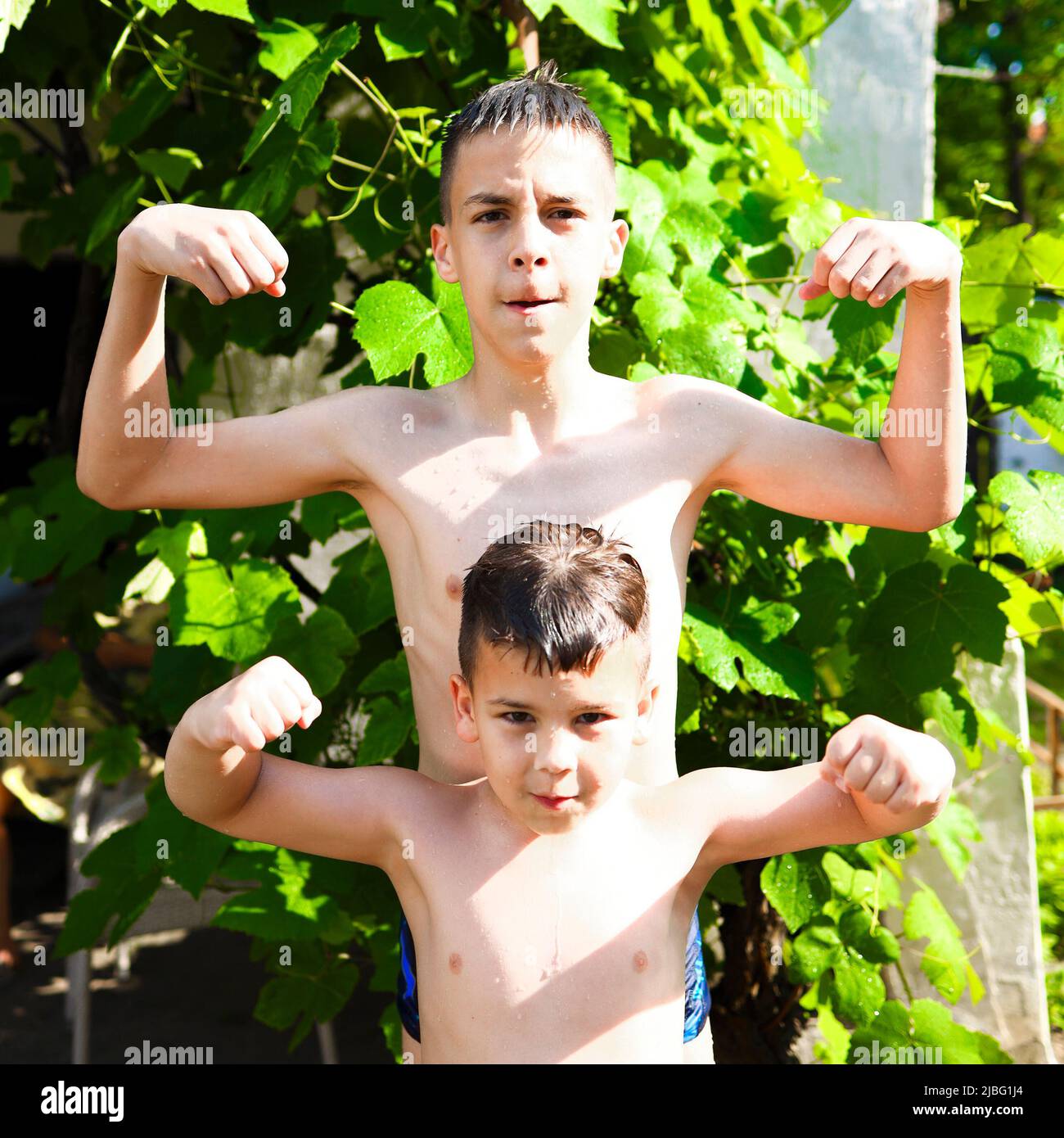 Due fratelli che mostrano i loro muscoli e goofing intorno in una giornata estiva soleggiata. Foto Stock