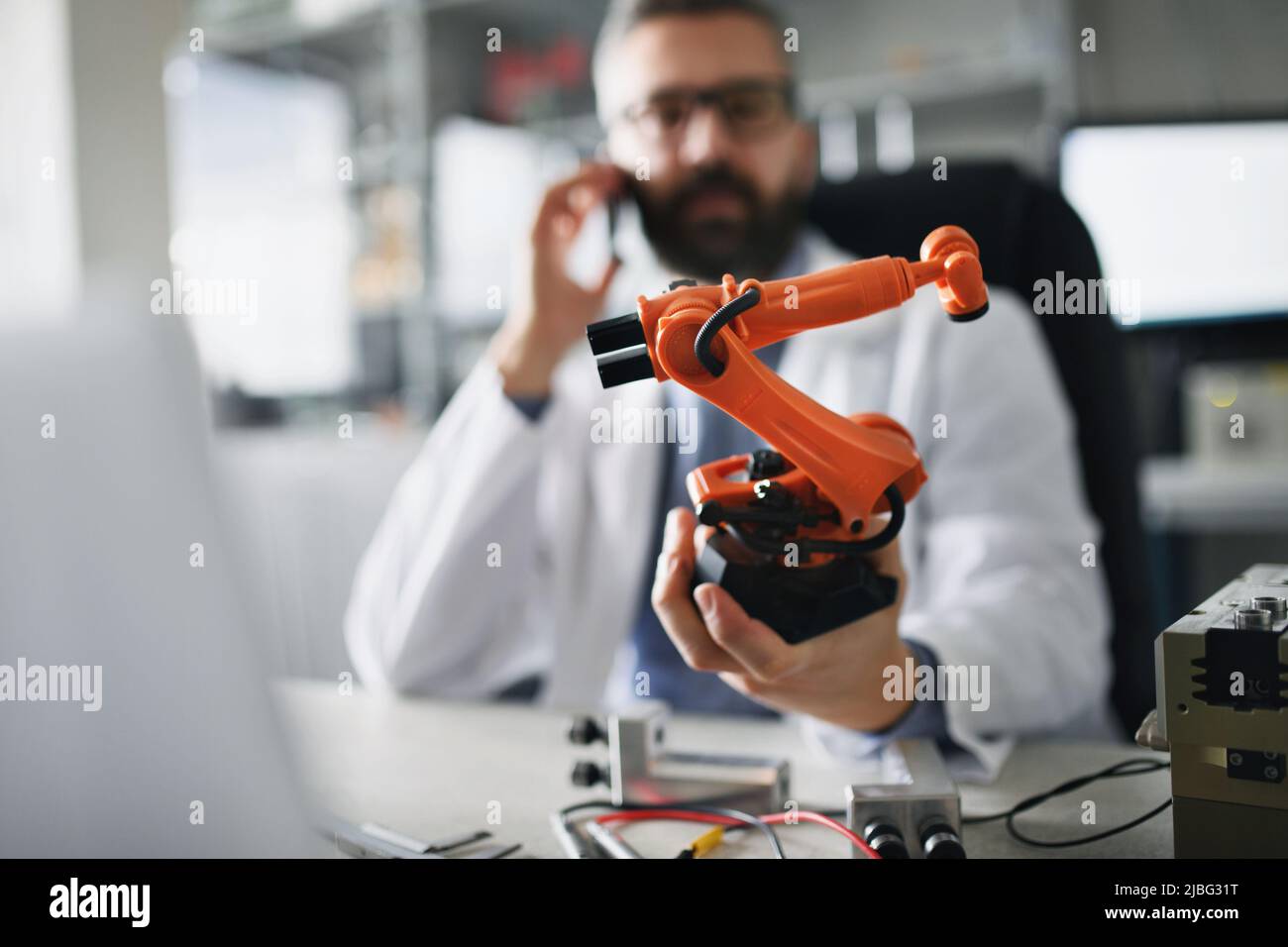 Robot braccio industriale in miniatura in mano a robot ingegnere che lavora su laptop in laboratorio. Foto Stock