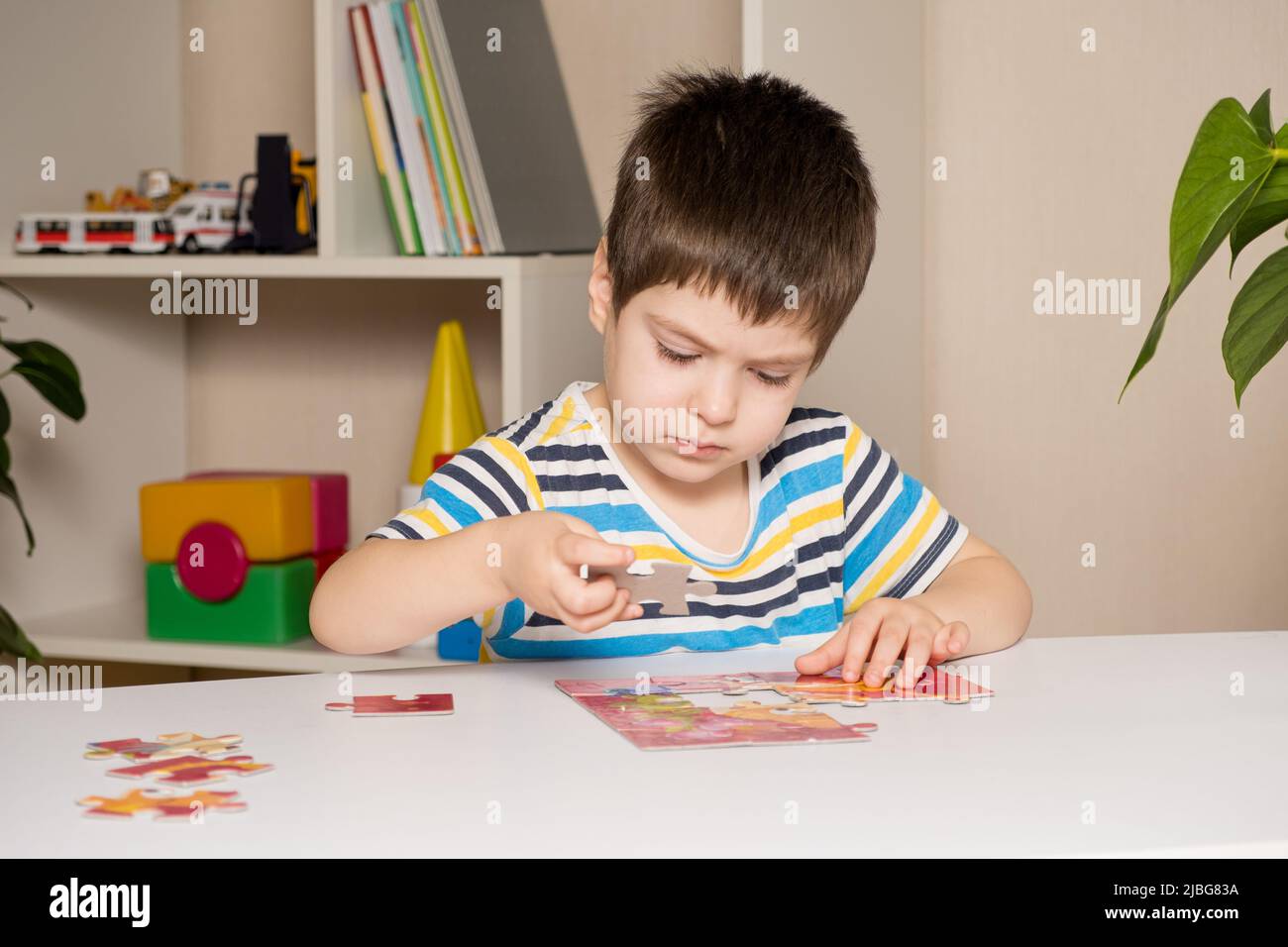 Un preschooler suona puzzle, mette insieme un'immagine Foto Stock