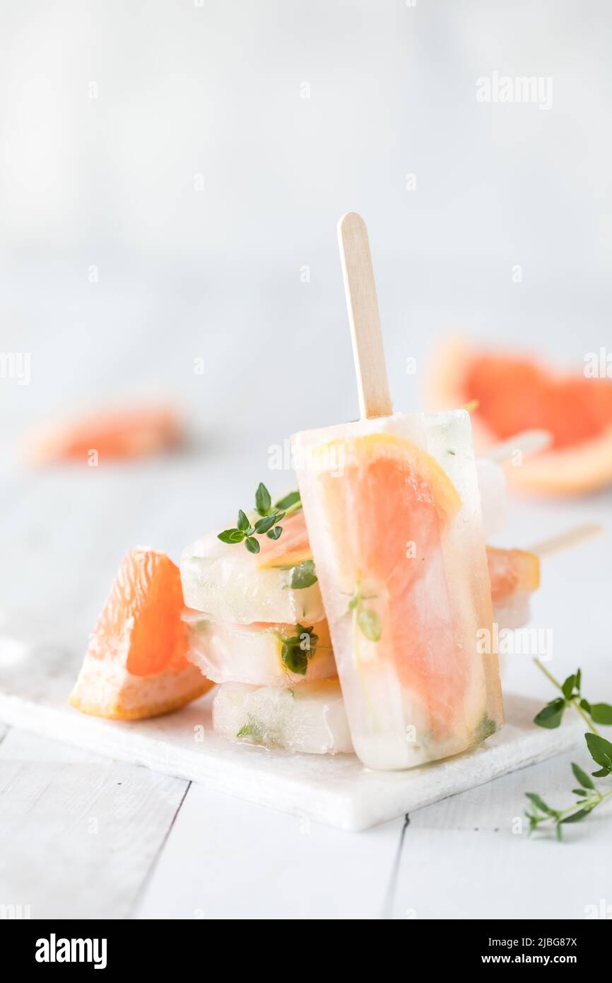 Un popsiclo di timo di pompelmo appoggiato contro una pila degli stessi papsicoli. Foto Stock