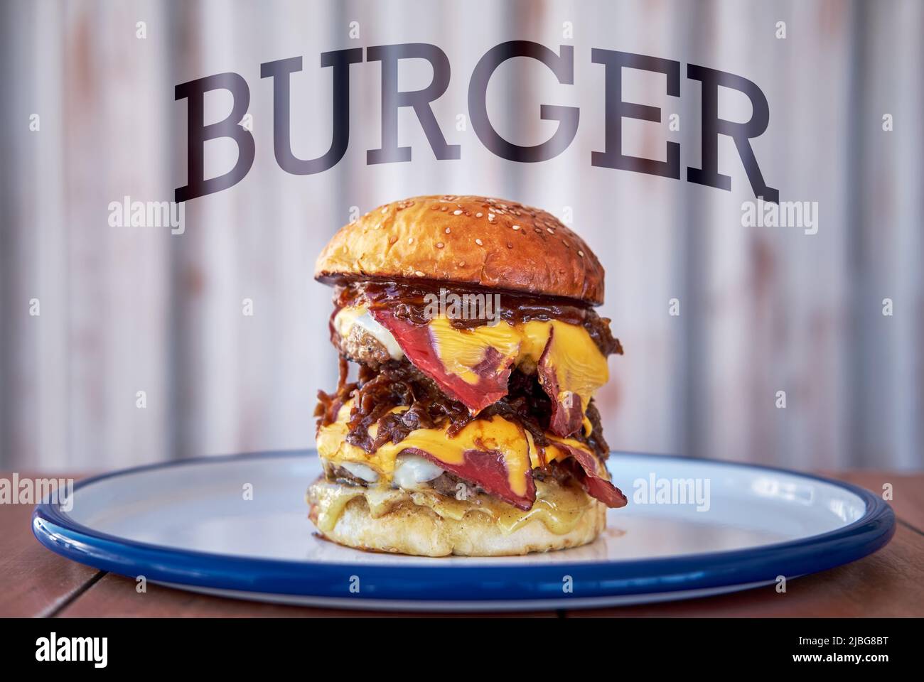 Un grande hamburger alto, hamburger o cheeseburger con affumicato incontro su un piatto Foto Stock