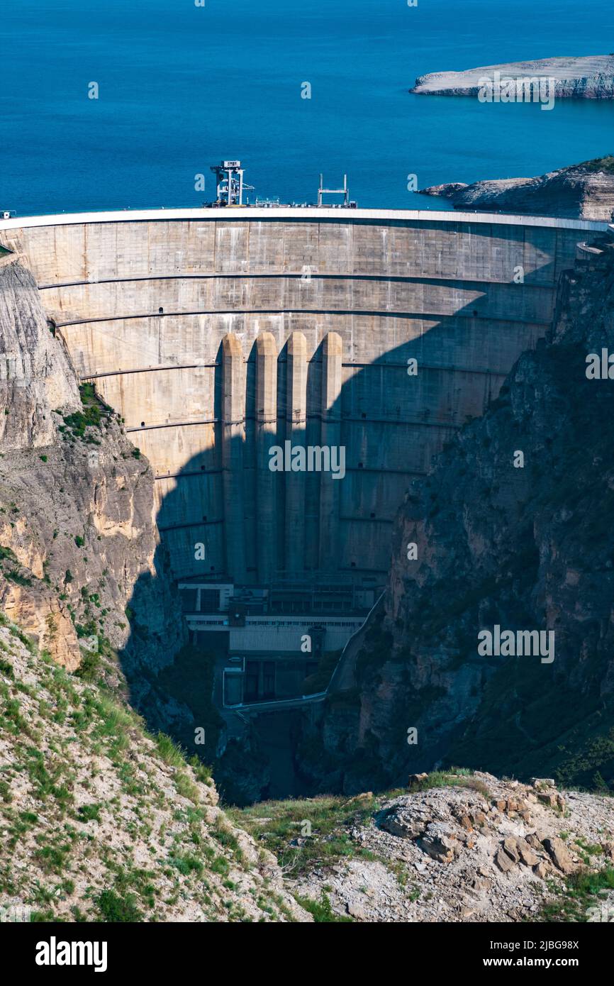 Vista della grande diga arco nel canyon, centrale idroelettrica Chirkey Foto Stock