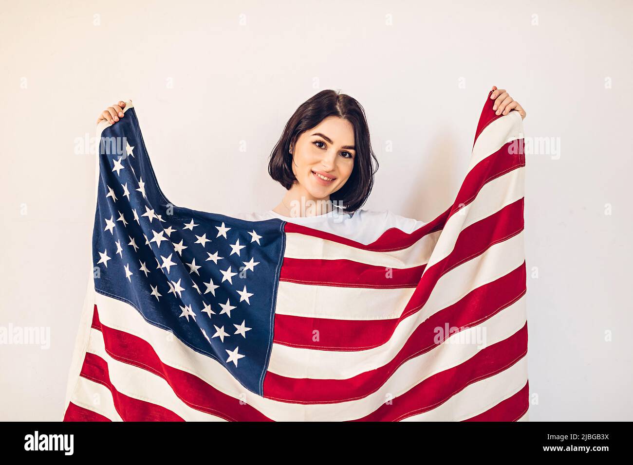 Ritratto lifestyle di una giovane ragazza felice che detiene una bandiera americana in US Independence Day, luglio 4th Foto Stock