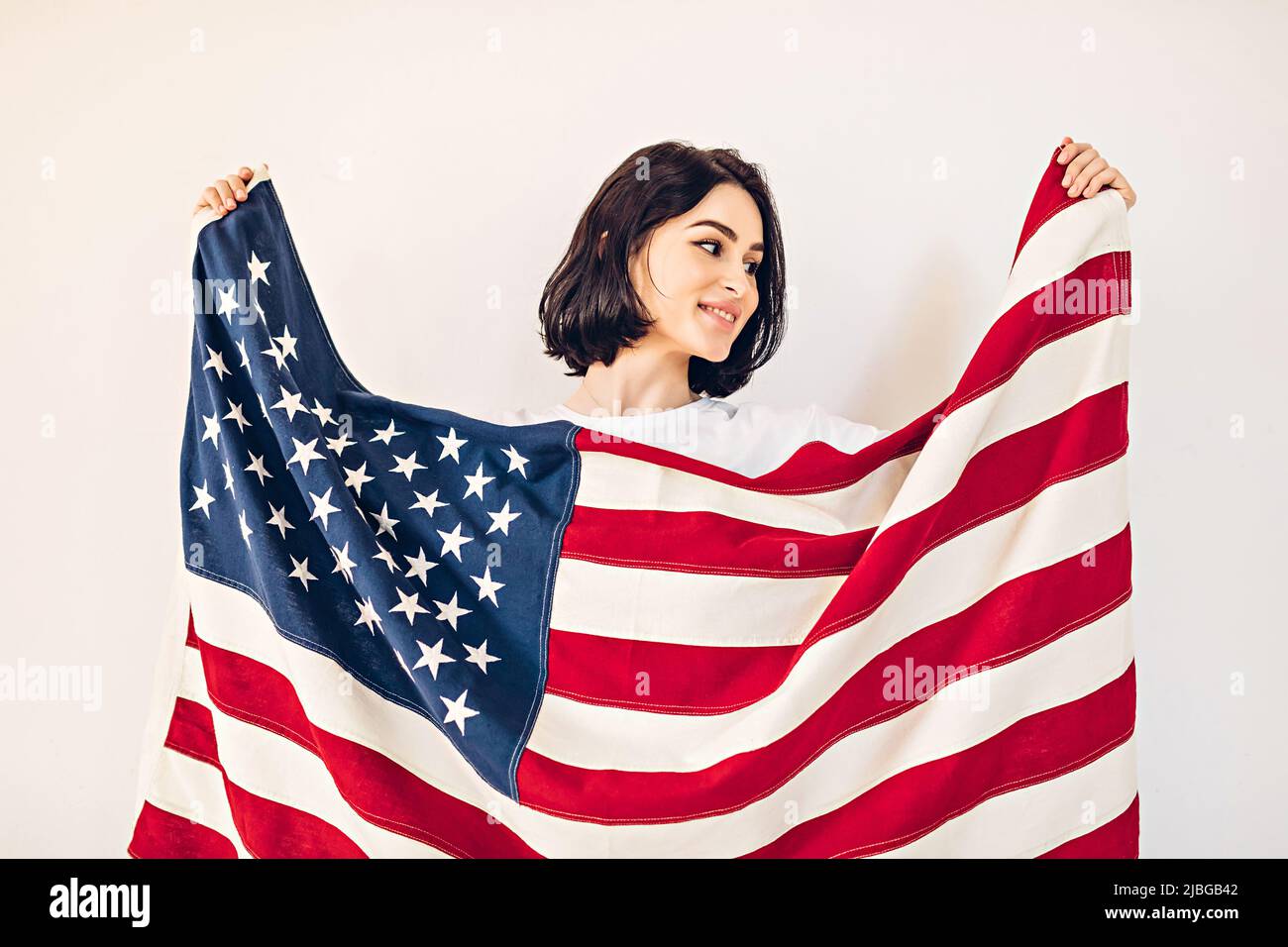 Ritratto lifestyle di una giovane ragazza felice che detiene una bandiera americana in US Independence Day, luglio 4th Foto Stock