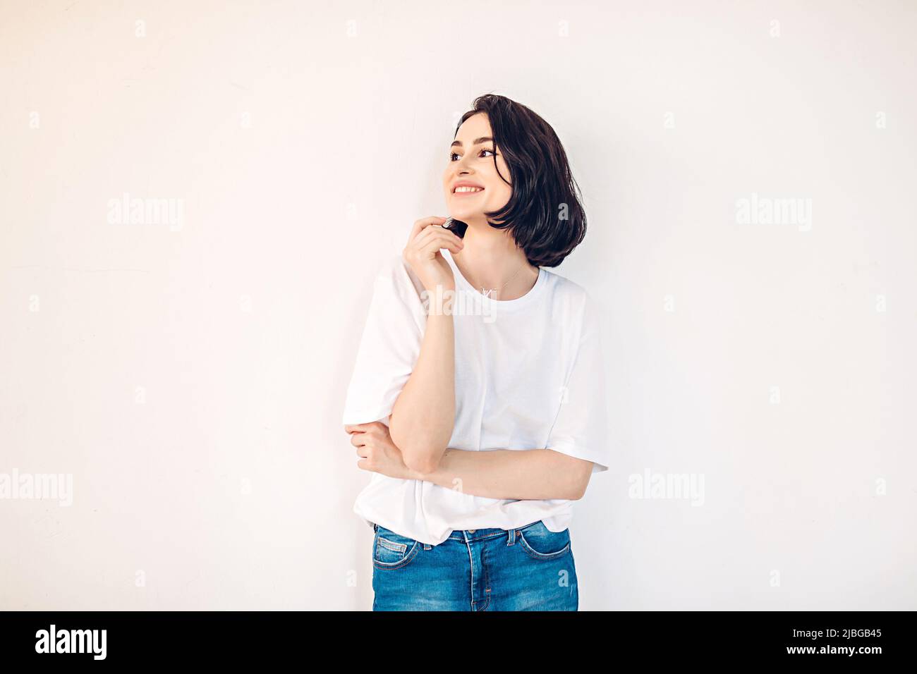 Ritratto lifestyle di una giovane ragazza felice che si diverte su uno sfondo bianco parete Foto Stock