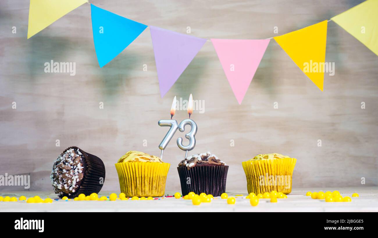 Sfondo compleanno con numero. Bella carta di compleanno con ghirlande colorate, un muffin con una candela che brucia copyspace. Foto Stock