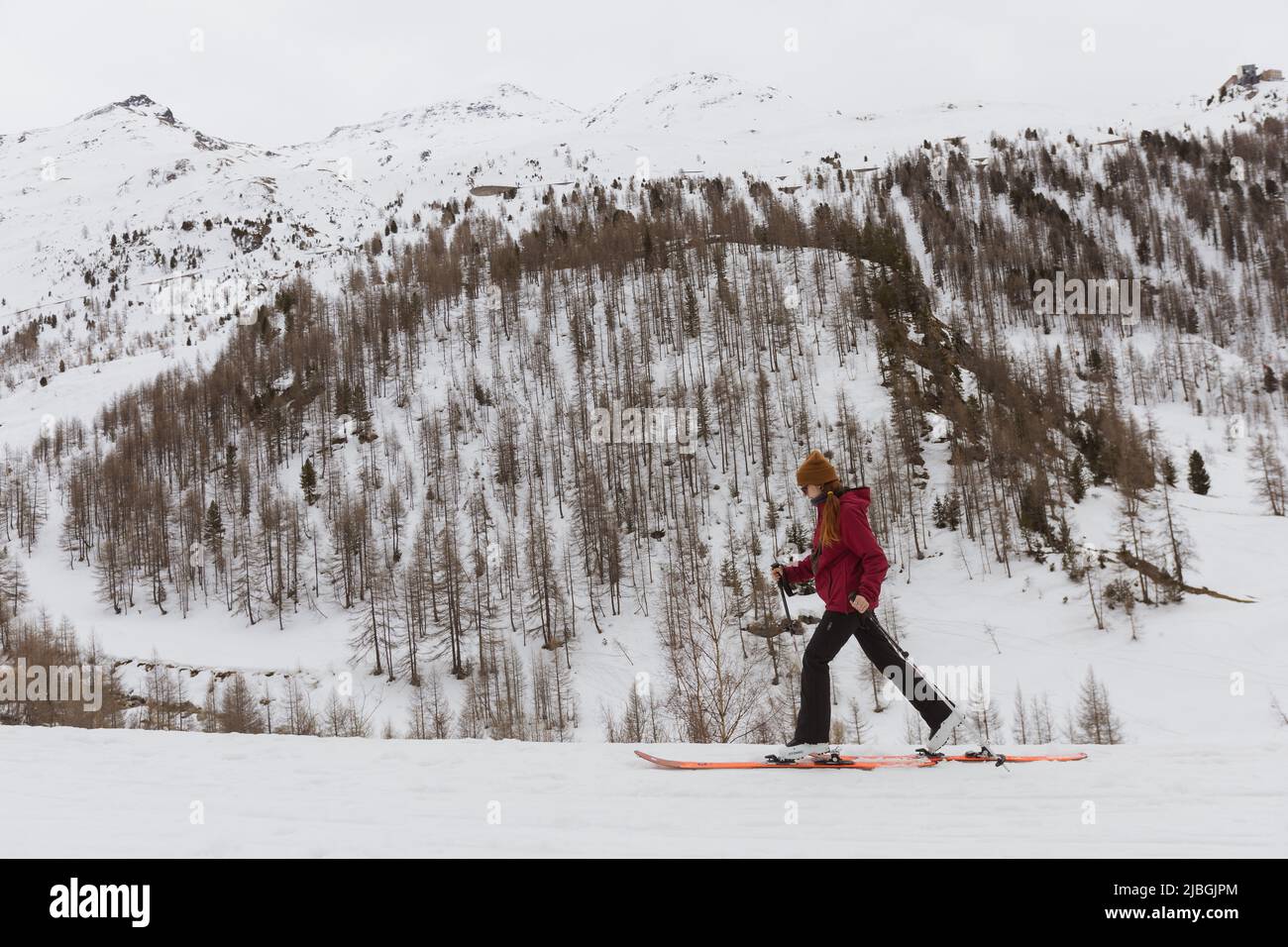 Una giovane donna con racchette da neve nella stazione sciistica della Val d’Isère nelle Alpi francesi Foto Stock