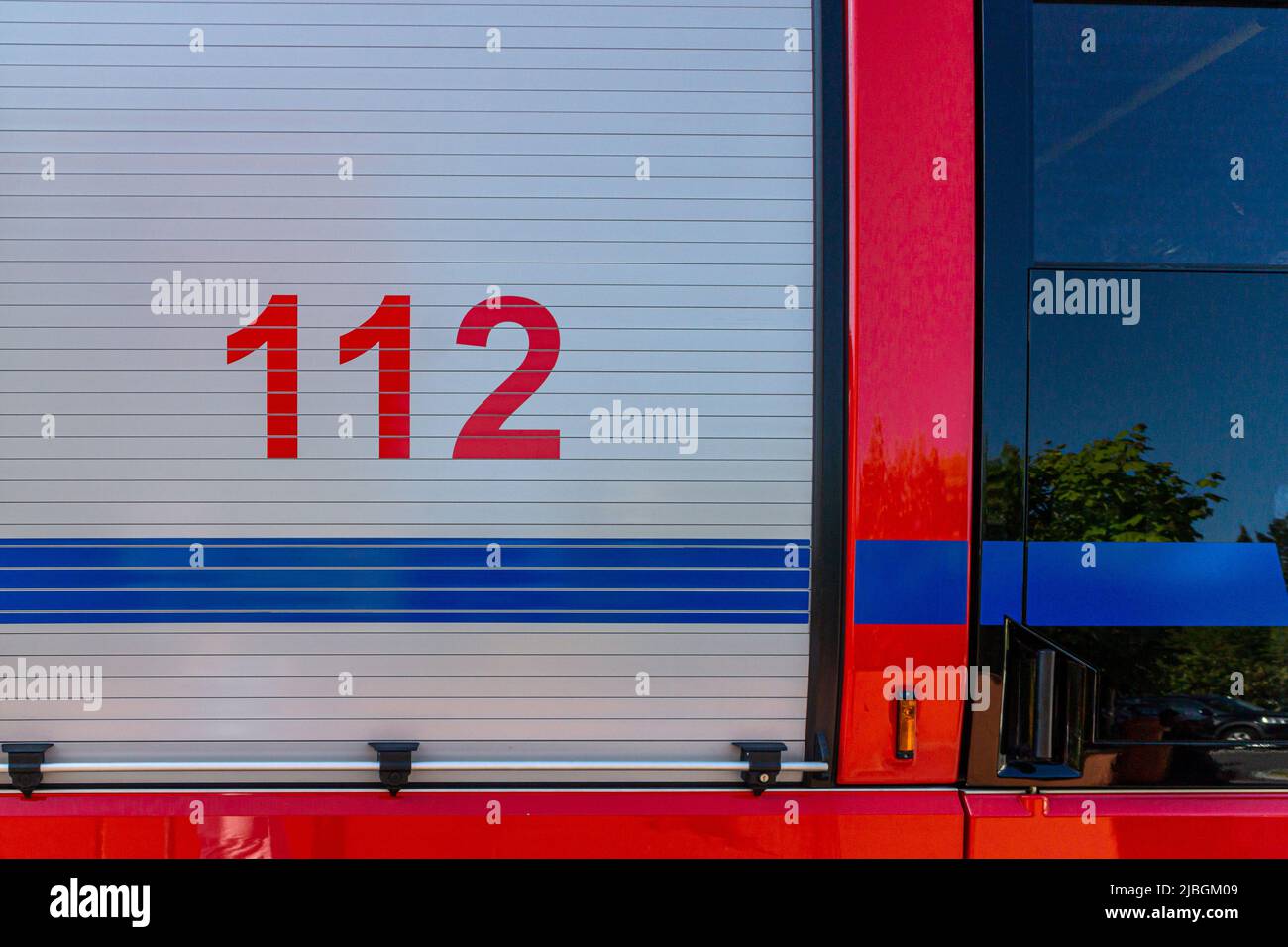 Sportello della serranda per camion antincendio su un motore antincendio tedesco con il numero di telefono di emergenza europeo 112 stampato Foto Stock