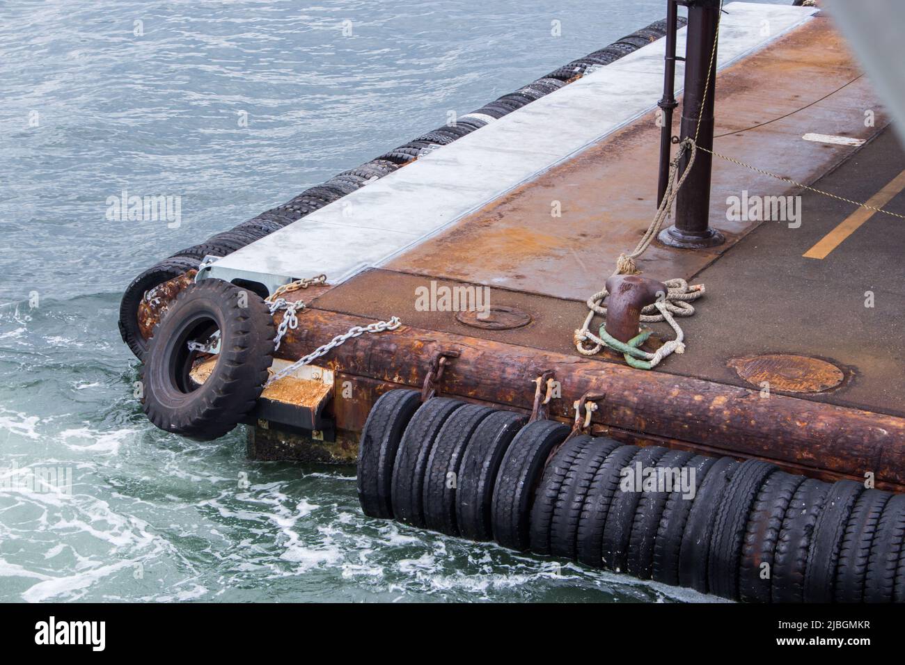 L'immagine di un piccolo molo arrugginito e pneumatici in mare, Hiroshima, Giappone. Foto Stock