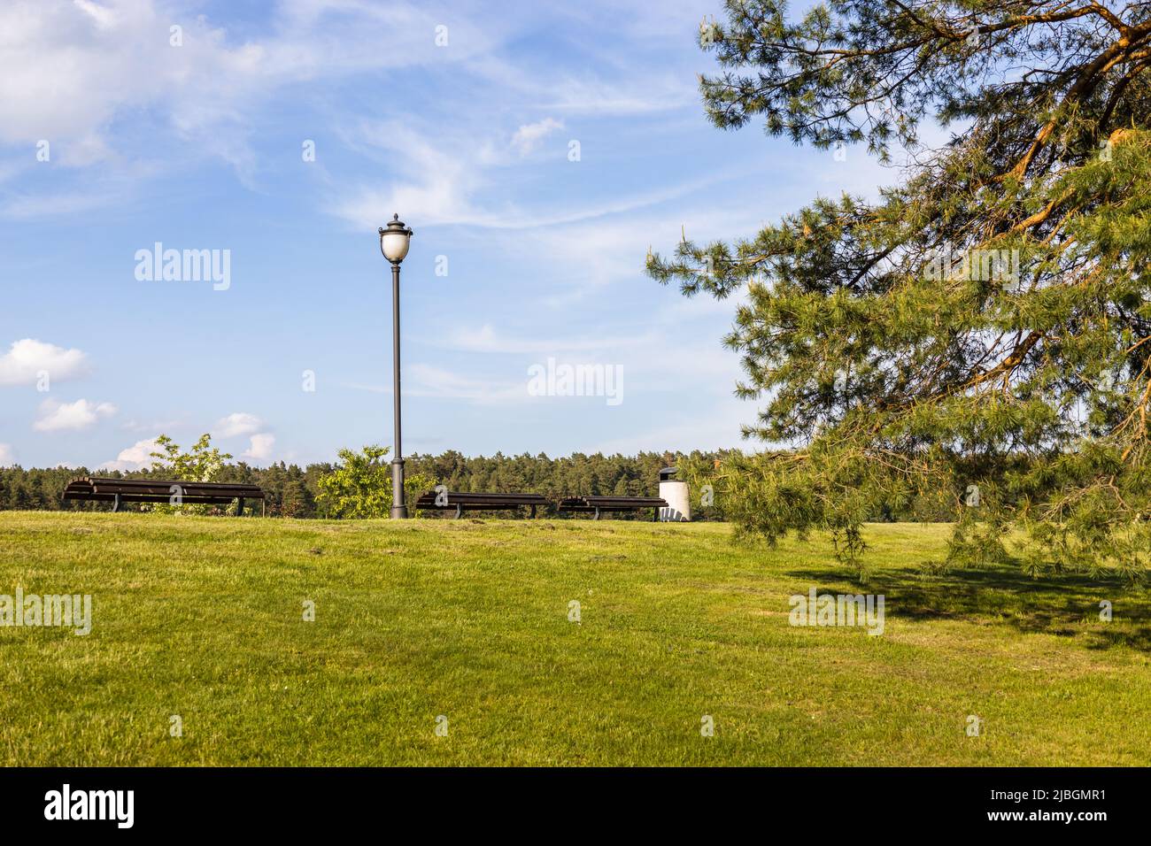 Panca di riposo e vecchia lampada moda nel parco della città Foto Stock
