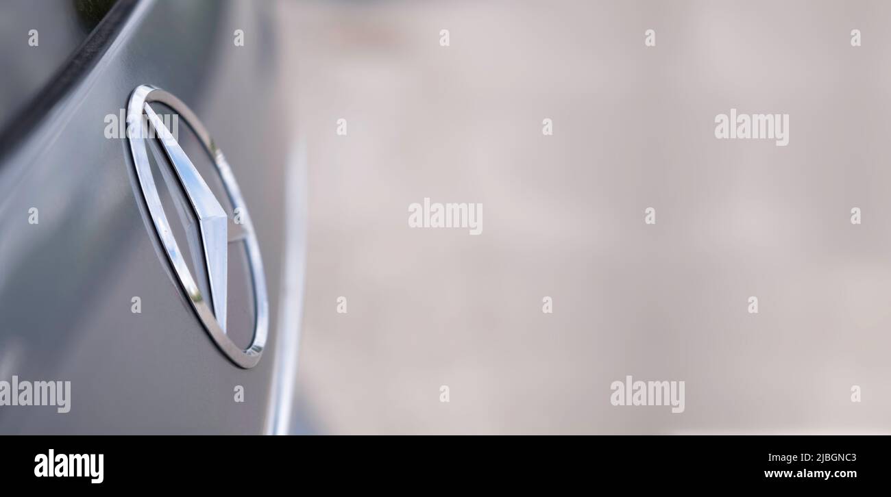 Logo a tre punte brillante del marchio Mercedes sul retro di un'auto. Vista ravvicinata. Spazio per testo e design sulla destra. Immagine di sfondo Foto Stock