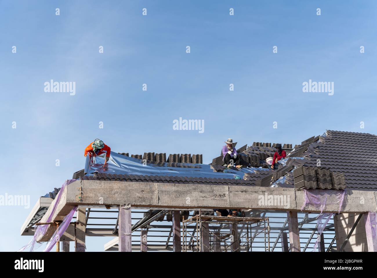 I tetti installano lamiere isolanti su un tetto di tegole in calcestruzzo. Foto Stock