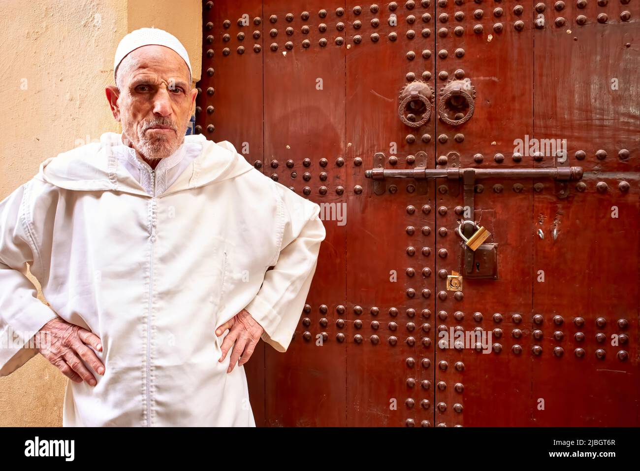 Marocco Fez. Ritratto di un vecchio uomo presso la vecchia porta d'ingresso della sua casa Foto Stock
