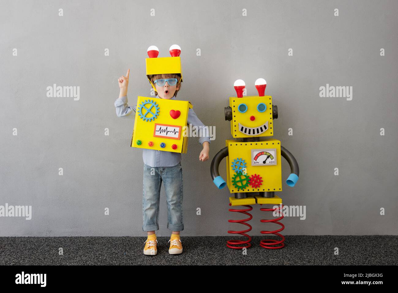 Bambino felice con robot. Divertente ragazzo hanno un'idea. Concetto di tecnologia di successo, creatività e innovazione Foto Stock