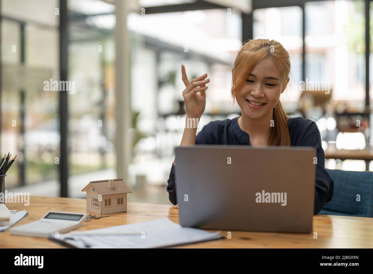 Ricerca in internet per immobili o nuova casa con modello di casa e chiave, giovane donna asiatica utilizzando computer portatile. Foto Stock