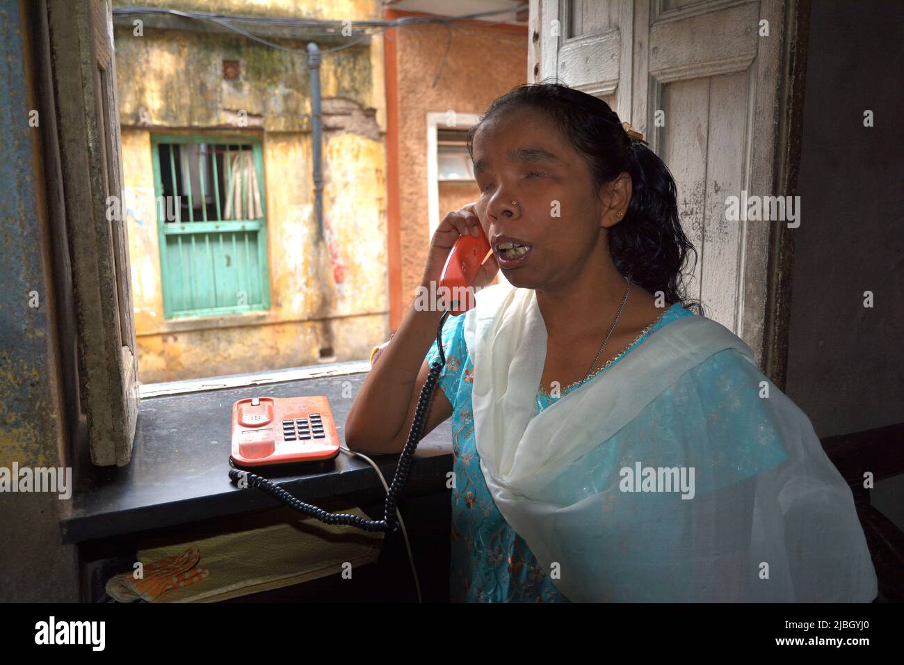 La donna cieca che chiama la sua amica tramite telefono tradizionale al mattino a Kolkata in India. Foto Stock