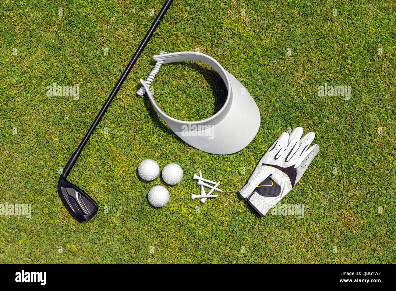 Vista dall'alto dell'attrezzatura da golf sull'erba verde di un campo da  golf. Piatto di golf club, palle, guanto, tee e cappello Foto stock - Alamy