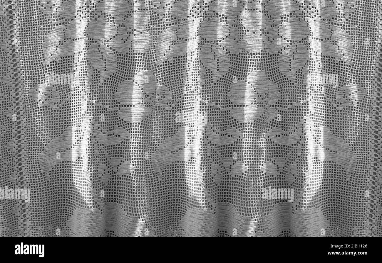 Tenda a crochet bianca con decorazioni floreali appende al sole. Illuminato di lato Foto Stock