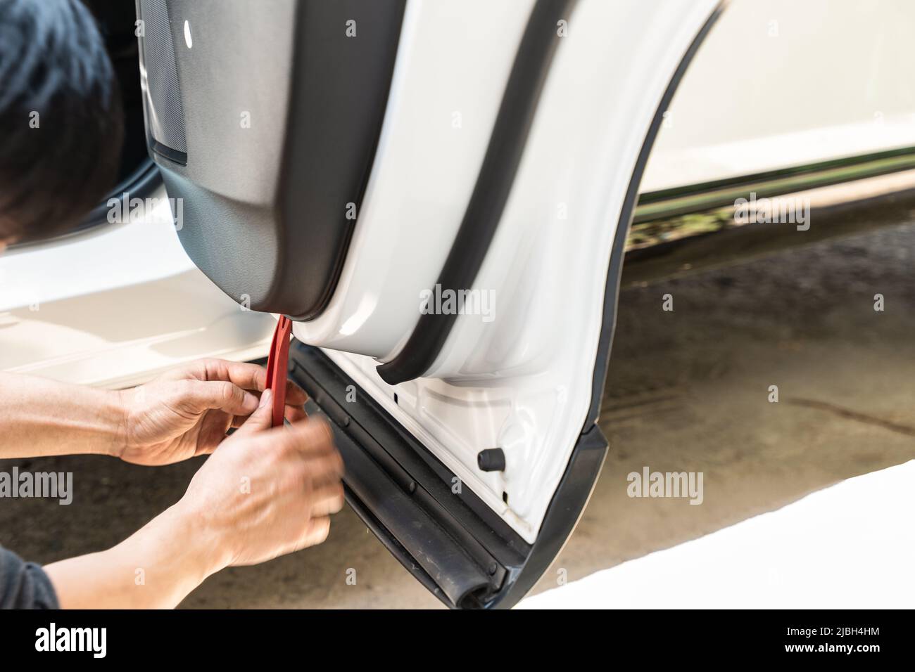 Mano del meccanico utilizzando un cuneo rimuovendo e installando una camma del cruscotto all'interno di un'automobile all'officina del garage Foto Stock