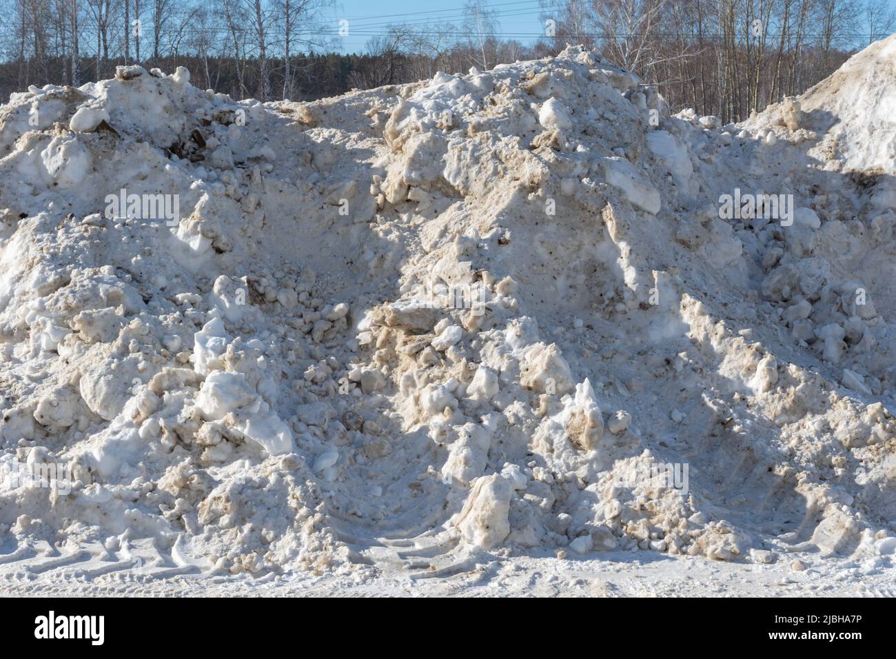 Grandi mucchi di neve sul lato della strada per le automobili. Alte nevicate dopo una nevicata o una bufera. Sgombrare la neve su strada per una guida sicura Foto Stock