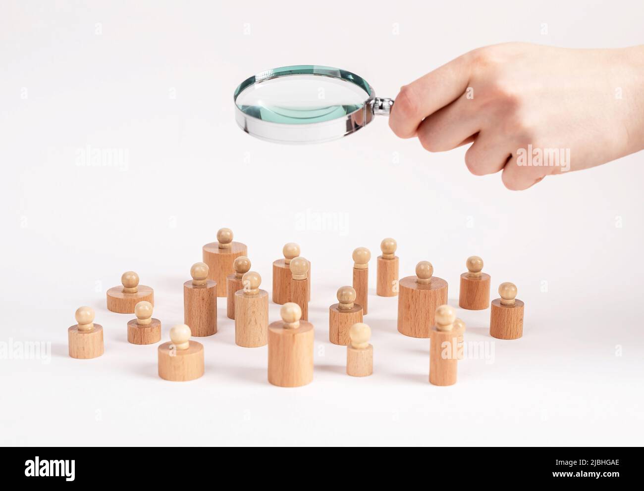 Ricerca sociale. Mano con lente d'ingrandimento sopra Montessori bombole knobbed come la comunità delle persone. Concetto di sociologia. Foto di alta qualità Foto Stock