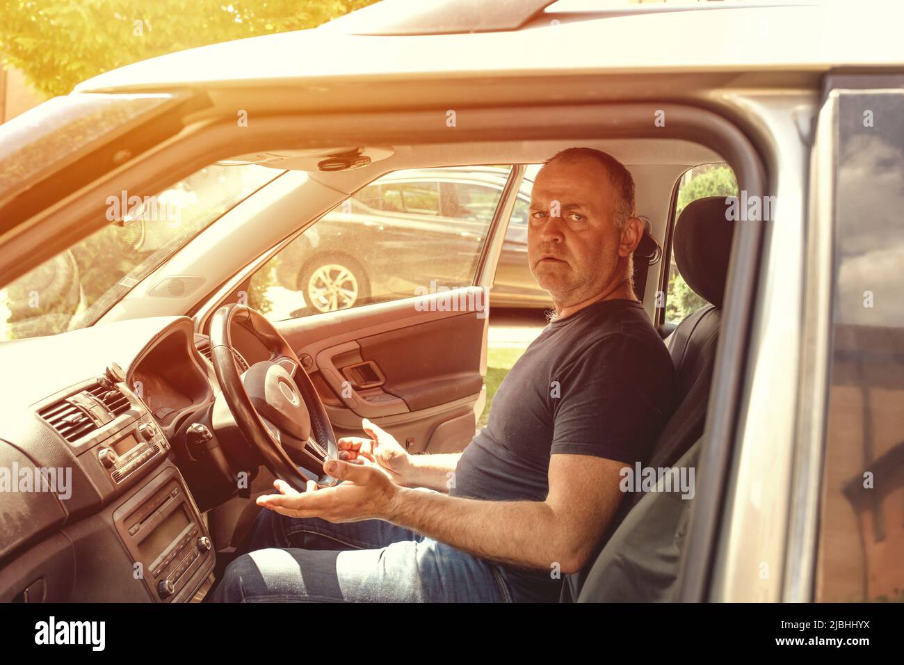 Un uomo seduto in un'auto e che cerca di avviare il motore dopo la riparazione Foto Stock