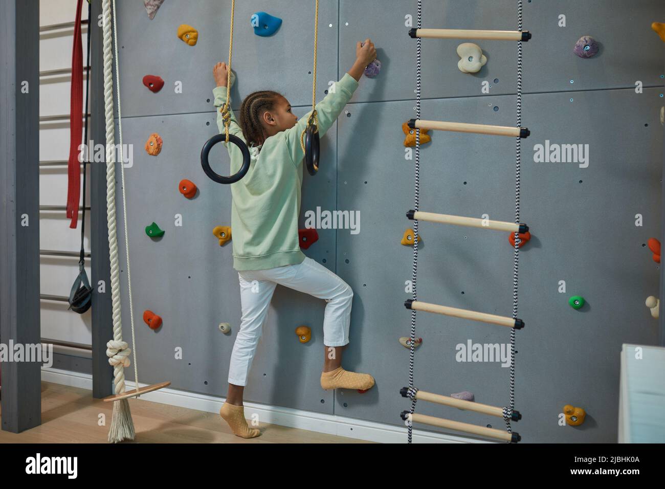 Ritratto di bambino nero attivo parete di arrampicata su casa sport set, copia spazio Foto Stock