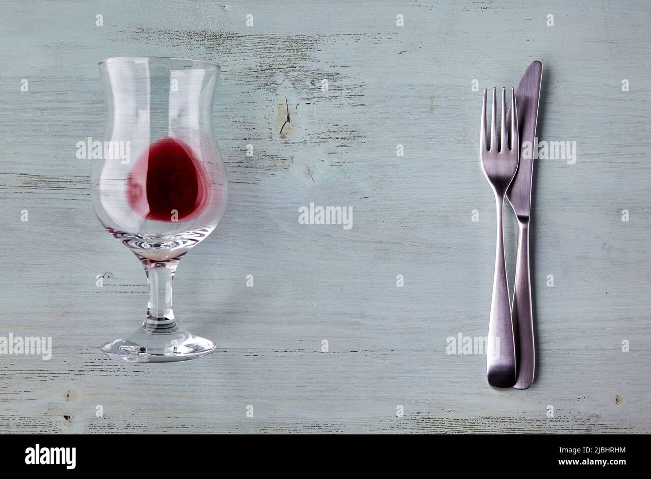 Un bicchiere di vino e posate su un tavolo di legno blu chiaro. Mostra di cibo mockup Foto Stock