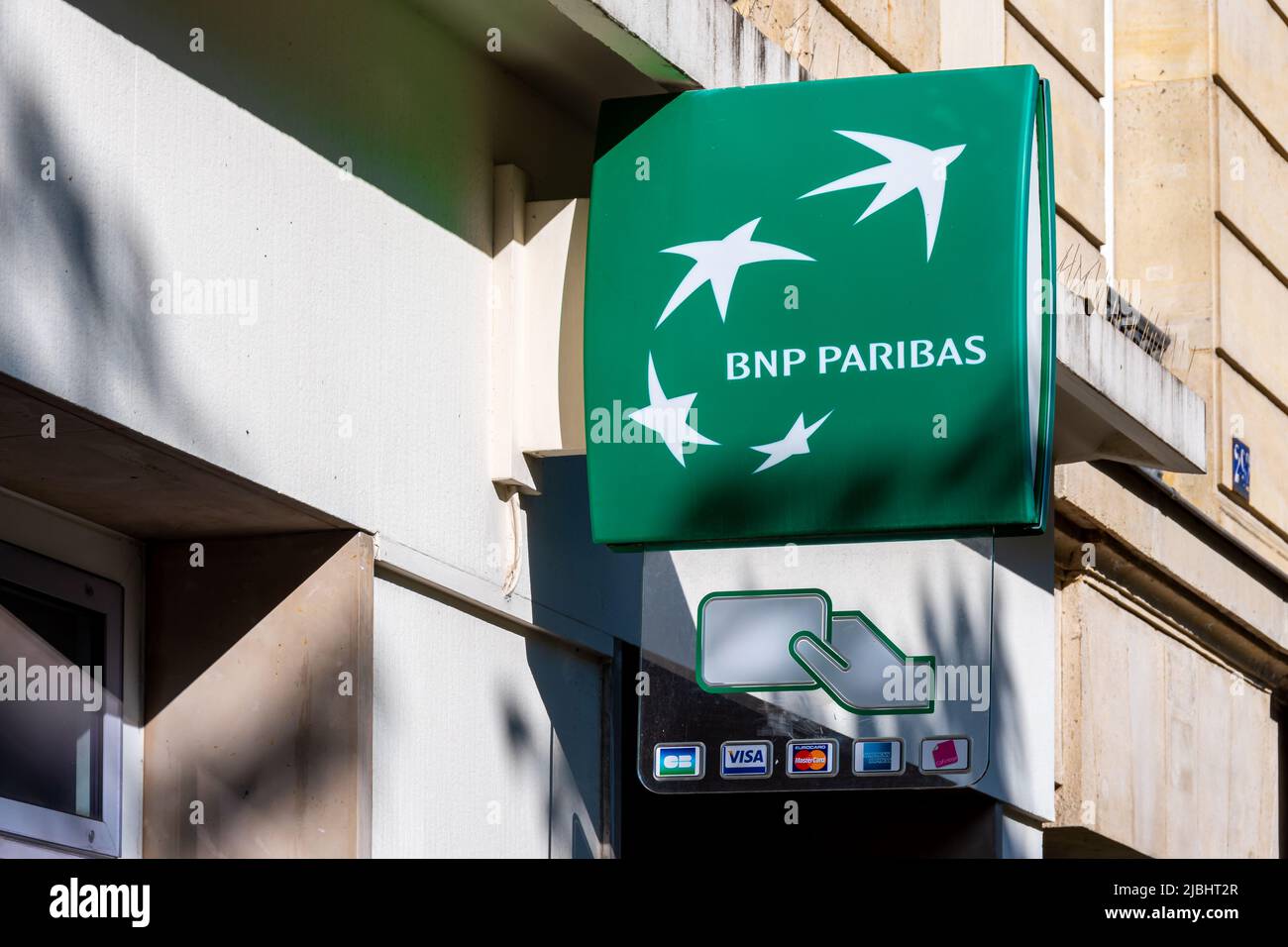 Segno e logo della banca francese BNP Paribas all'esterno di una filiale di Parigi che indica la presenza di un bancomat Foto Stock