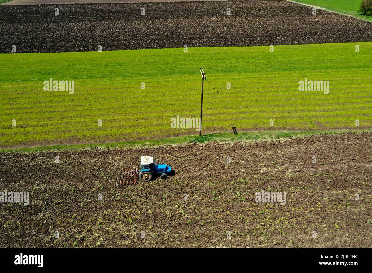 Vista aerea del trattore agricolo che aratura in campo, trattore che prepara in primavera il coltivatore a base di terreno seminato Foto Stock
