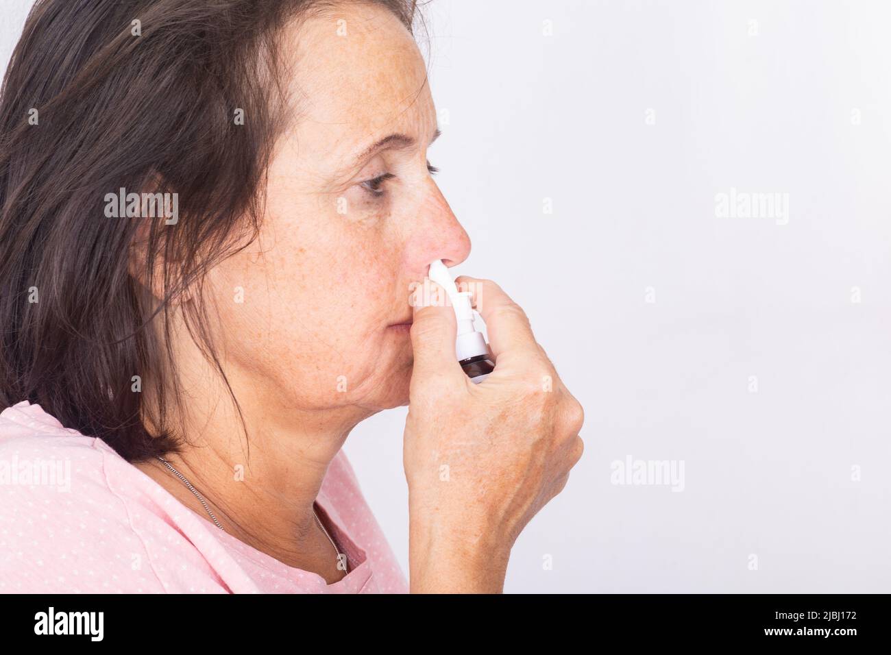 Vista laterale di una donna con spray nasale - isolato. Foto Stock
