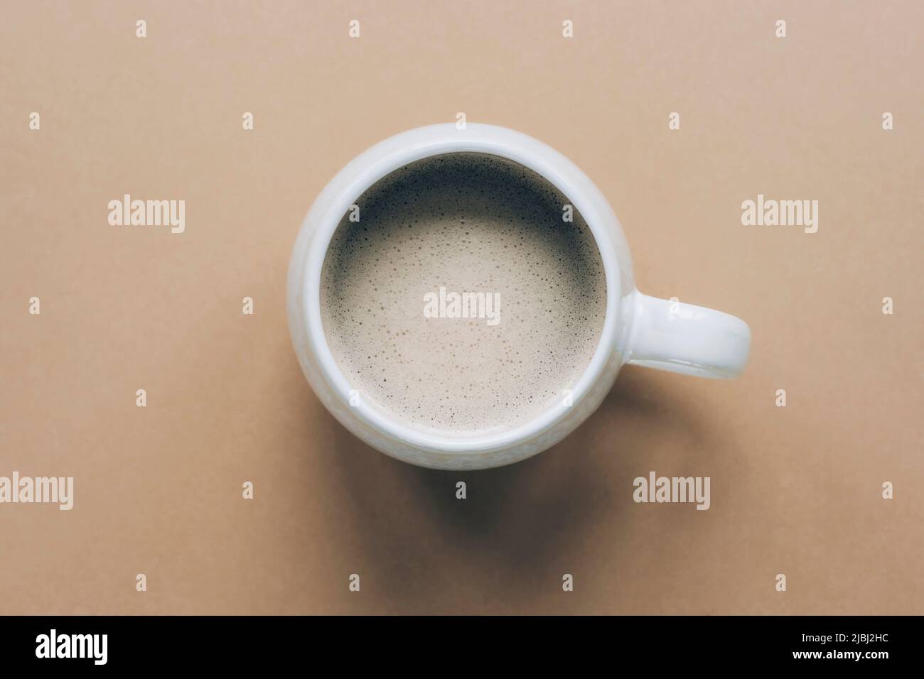 Una tazza di caffè con schiuma su sfondo neutro. Vista dall'alto, piatto. Foto Stock
