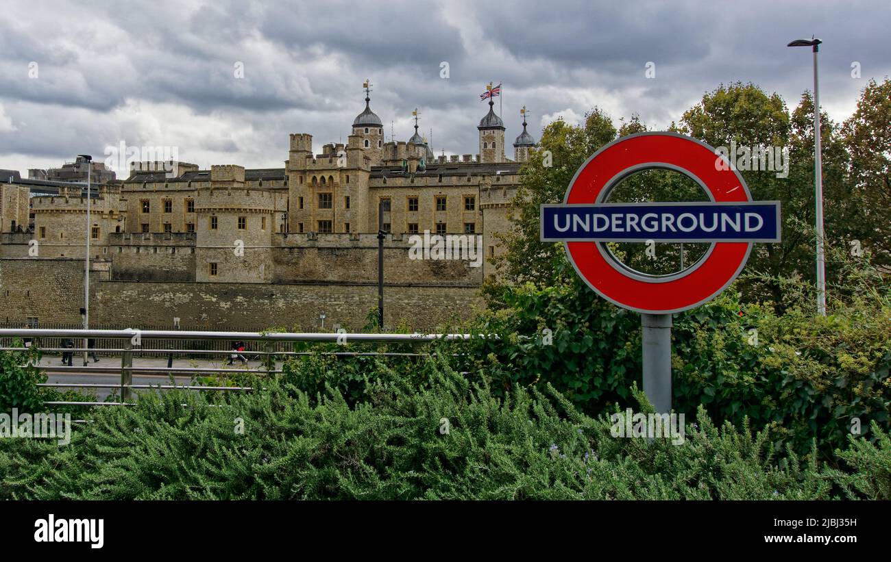 Londra, Inghilterra - 17 ottobre 2019: Il Palazzo medievale la Torre di Londra è giustapposta con un moderno cartello della metropolitana di Londra. Foto Stock