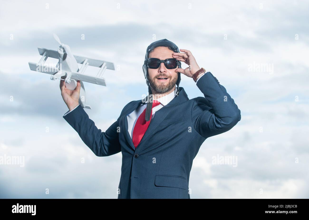 uomo d'affari allegro in abito e cappello pilota lancio aereo giocattolo Foto Stock