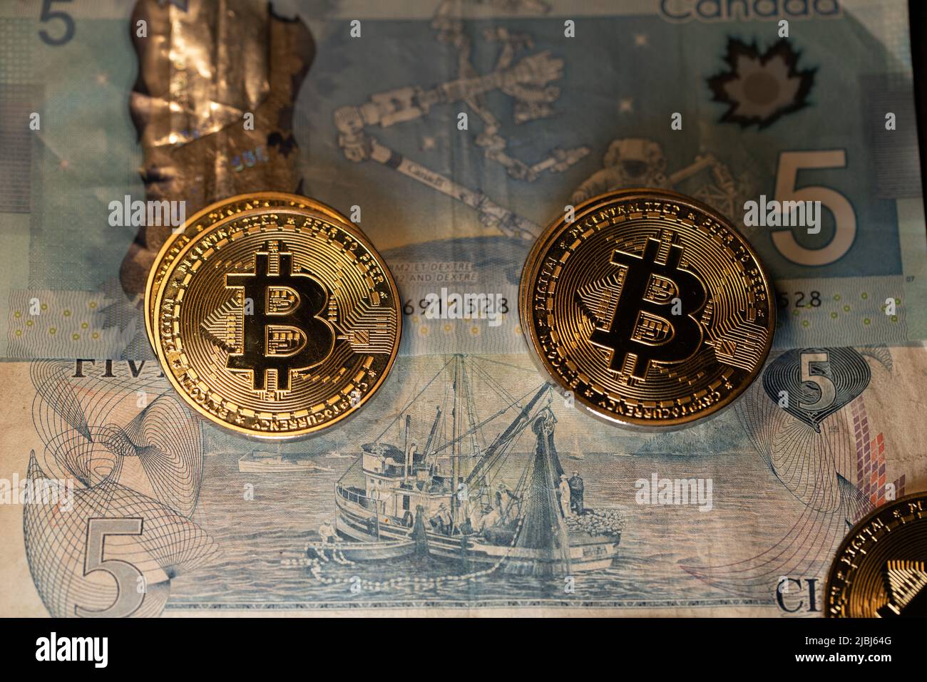 Toronto, Canada - Ottobre 30. 2021: Bitcoin su cinque banconote in dollari canadesi. Fatture CAD e monete d'oro Bitcoin. Criptovaluta commerciale in Canada conc Foto Stock