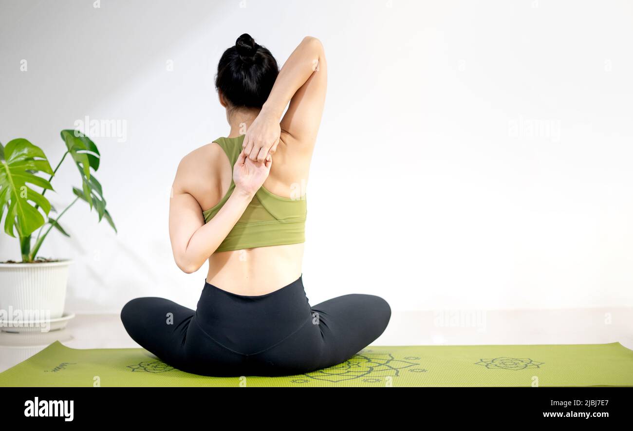 Donna che fa yoga sul tappeto verde yoga per meditare ed esercitare in casa. Foto Stock