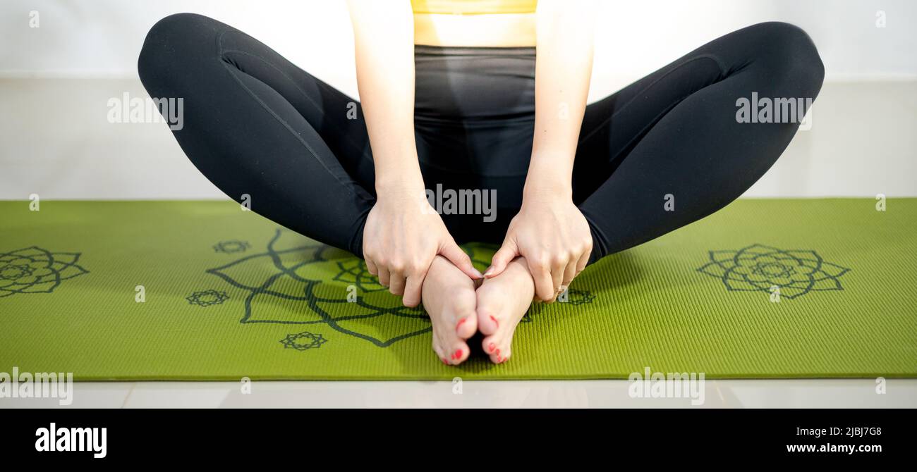 Donna che fa yoga sul tappeto verde yoga per meditare ed esercitare in casa. Foto Stock