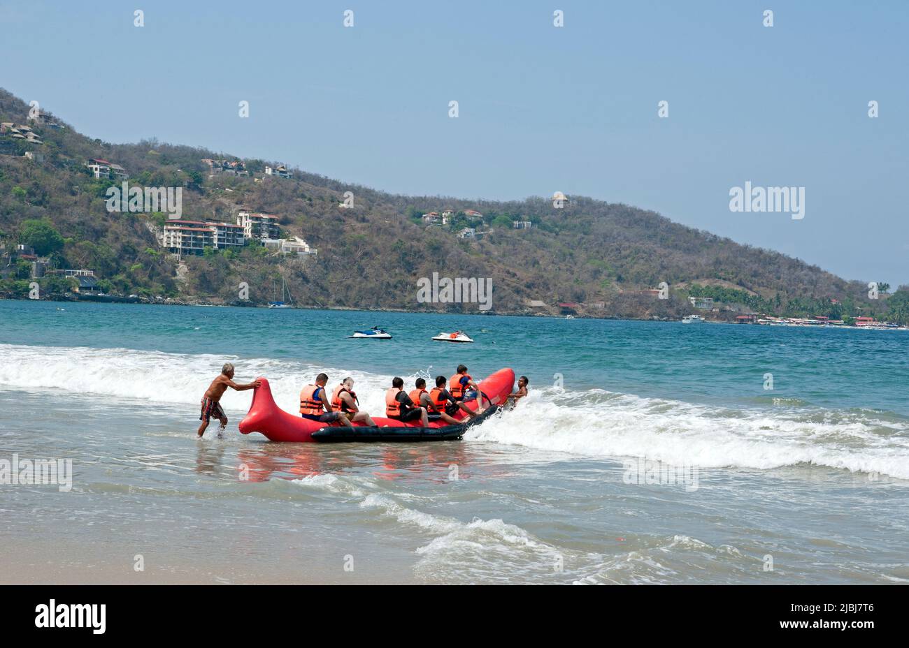 I visitatori di Playa la Ropa si preparano a fare un giro su una grande barca gonfiabile a Zihuatanejo, Messico Foto Stock