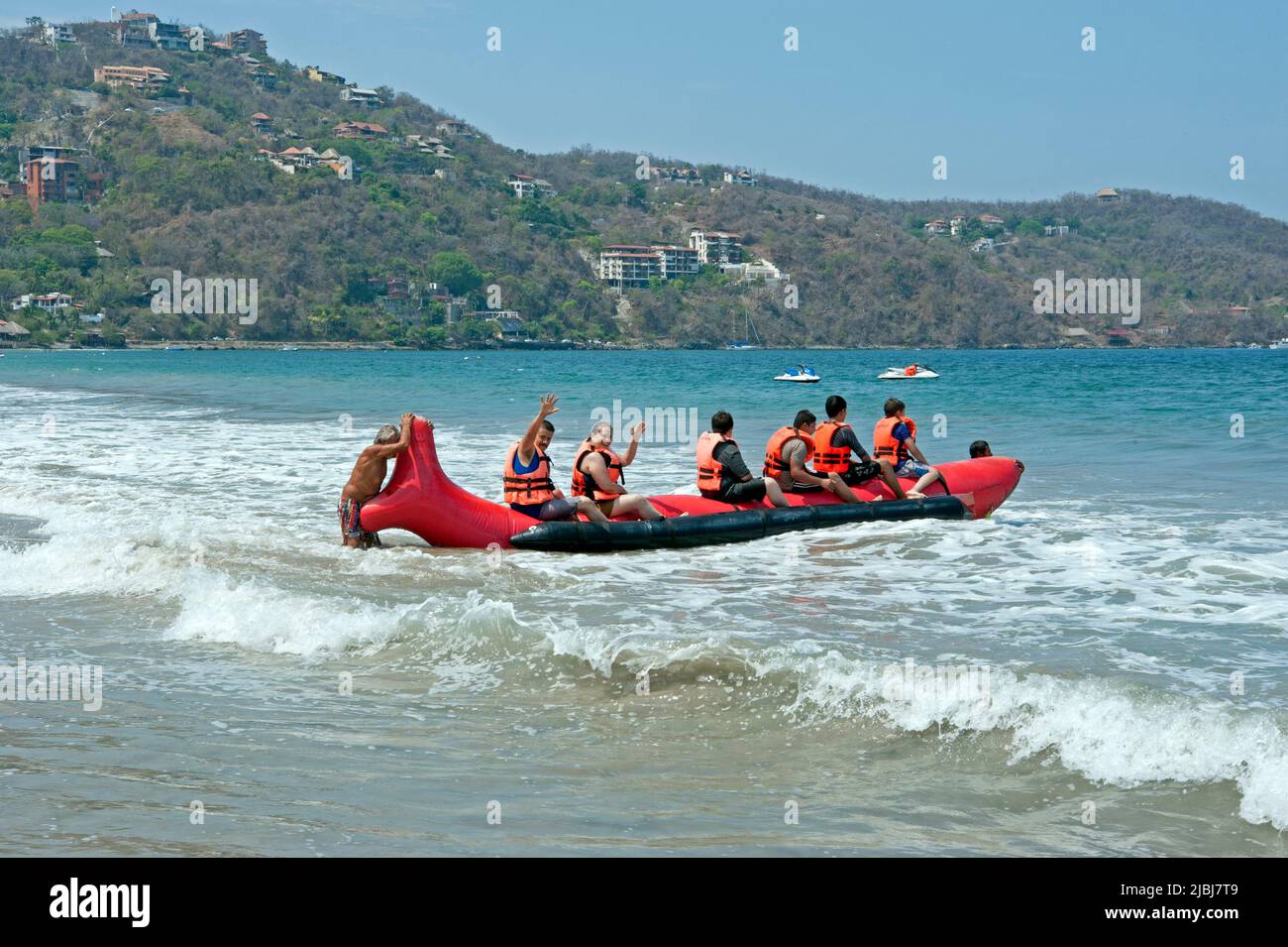 I visitatori di Playa la Ropa si preparano a fare un giro su una grande barca gonfiabile a Zihuatanejo, Messico Foto Stock